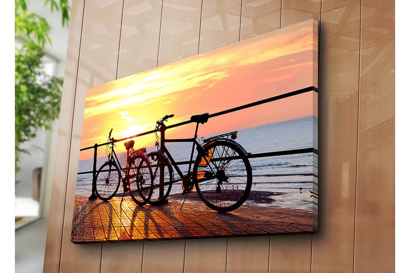 Lerretsbilde 70x100 cm - To sykler som står på en brygge ved solnedgang over havet - Oransje / Svart / Gul - Innredning - Bilder & kunst - Lerretsbilder