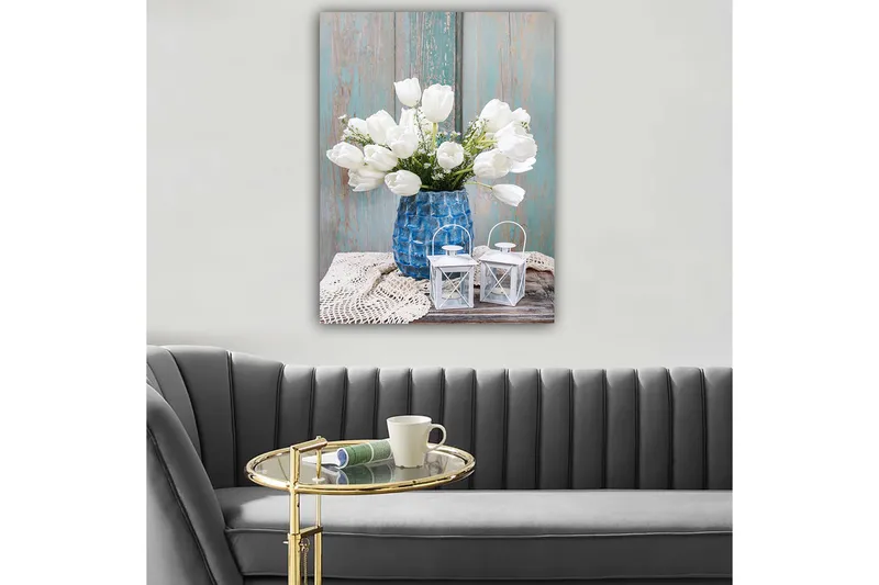 Lerretsbilde 70x100 cm - Vakker bukett med hvite tulipaner i en blå vase, plassert på en treoverflate med lyse detaljer, Hvit / Blå / Grå