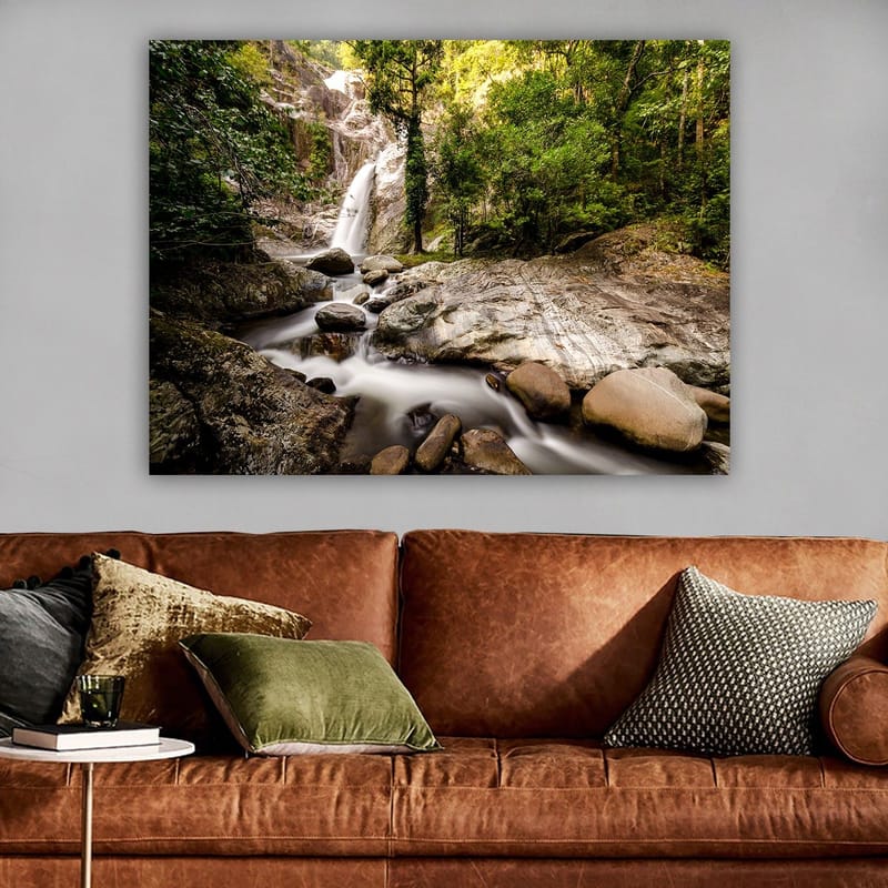 Lerretsbilde 70x100 cm - Vakker fossescene omgitt av frodig grøntområde og steinblokker - Grønn / Grå / Brun - Innredning - Bilder & kunst - Lerretsbilder