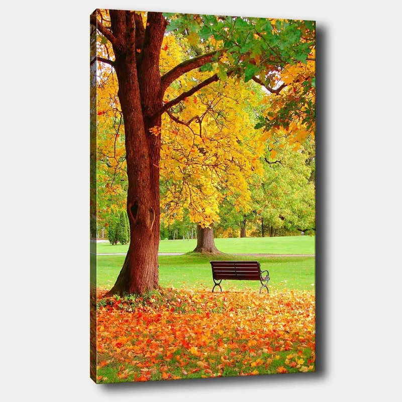 Lerretsbilde 70x100 cm - Vakker høstscene med en benk under et fargerikt tre, Gyllengul / Oransje / Brun