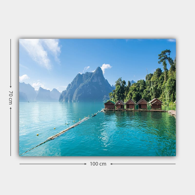 Lerretsbilde 70x100 cm - Vakker innsjø med hytter ved vannet, omgitt av majestetiske fjell og frodig skog - Turkis / Grønn / Brun - Innredning - Bilder & kunst - Lerretsbilder