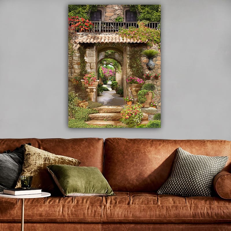 Lerretsbilde 70x100 cm - Vakker og frodig hage med blomsteroppsatser og en steinbue som fører inn til en løvrik gangvei - Grønn / Rosa / Beige - Innredning - Bilder & kunst - Lerretsbilder