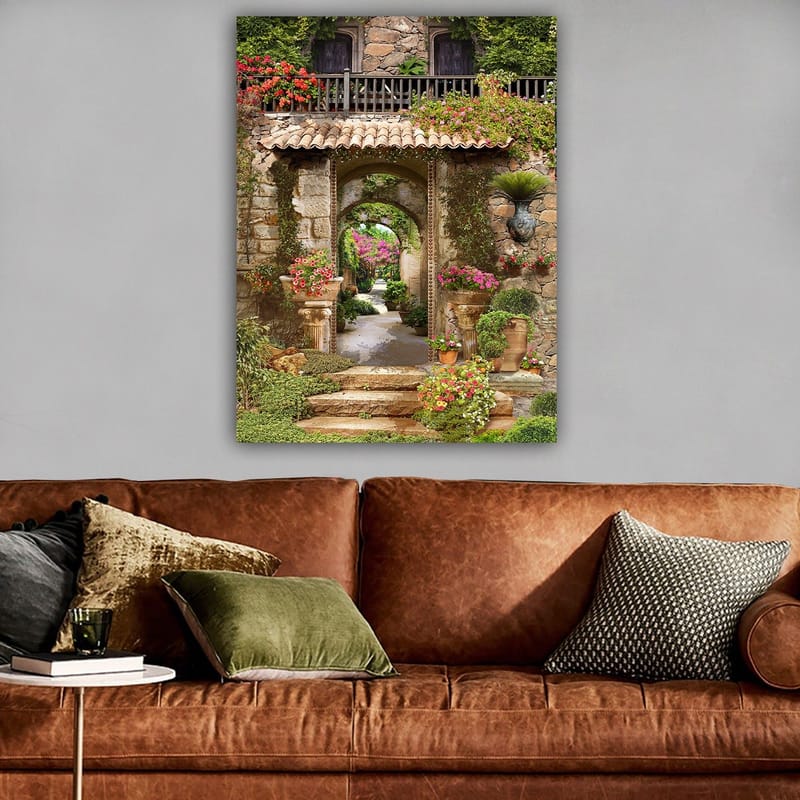 Lerretsbilde 70x100 cm - Vakker og frodig hage med blomsteroppsatser og en steinbue som fører inn til en løvrik gangvei - Grønn / Rosa / Beige - Innredning - Bilder & kunst - Lerretsbilder