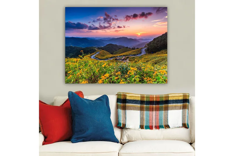 Lerretsbilde 70x100 cm - Vakker solnedgang over en blomstrende dal med svingete veier og fjell i bakgrunnen - Gul / Grønn / Blå - Innredning - Bilder & kunst - Lerretsbilder
