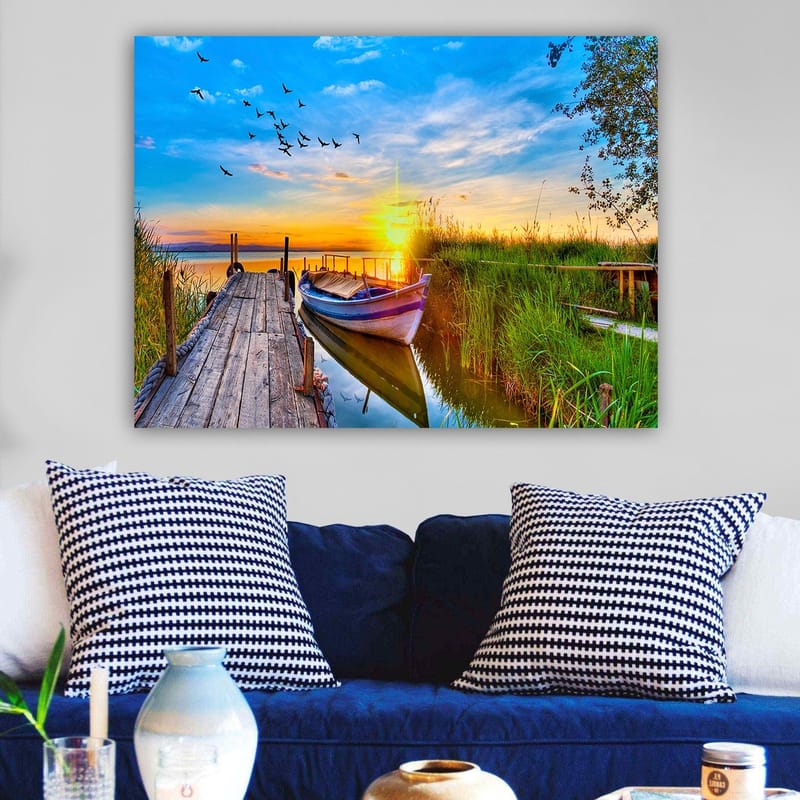 Lerretsbilde 70x100 cm - Vakker solnedgang over en rolig innsjø med en båt ved en trebrygge omgitt av grøntområder - Blå / Oransje / Grønn - Innredning - Bilder & kunst - Lerretsbilder