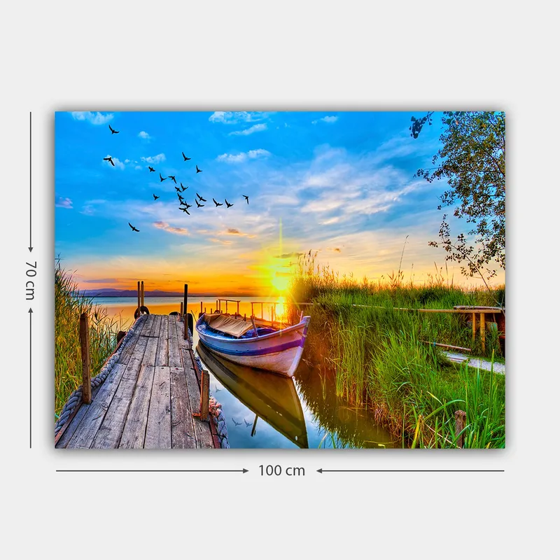 Lerretsbilde 70x100 cm - Vakker solnedgang over en rolig innsjø med en båt ved en trebrygge omgitt av grøntområder - Blå / Oransje / Grønn - Innredning - Bilder & kunst - Lerretsbilder