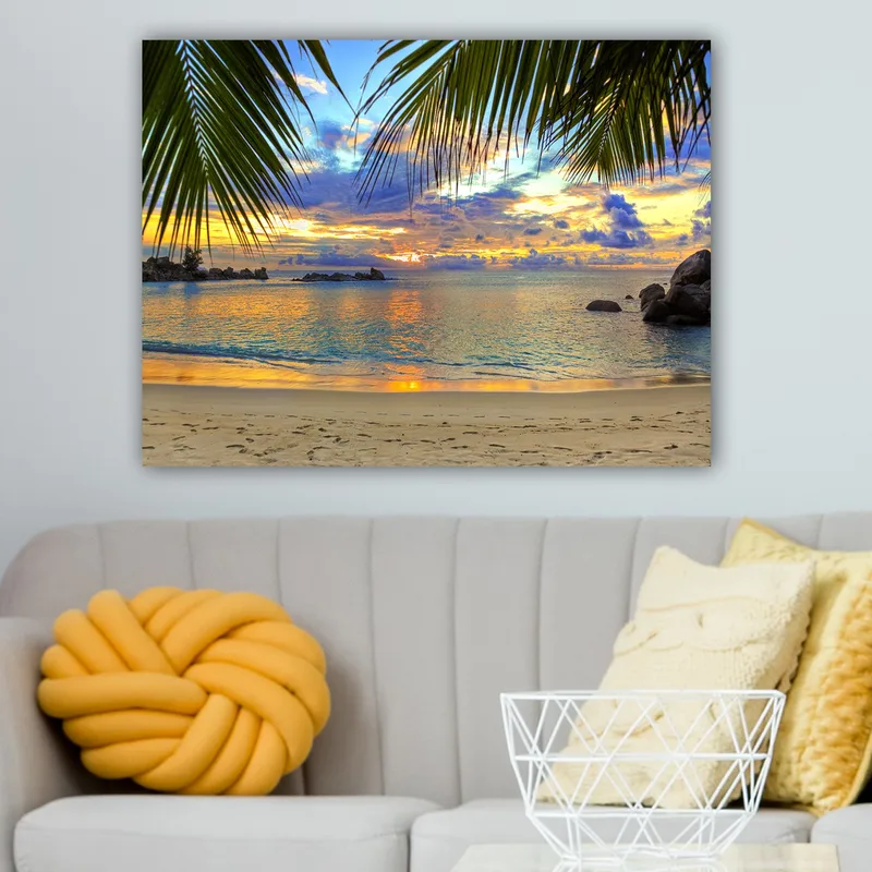 Lerretsbilde 70x100 cm - Vakker solnedgang over en strand med palmer som rammer inn motivet - Blå / Oransje / Grønn - Innredning - Bilder & kunst - Lerretsbilder