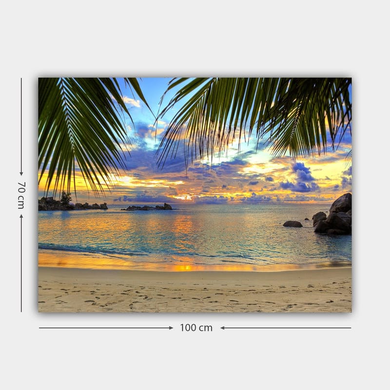 Lerretsbilde 70x100 cm - Vakker solnedgang over en strand med palmer som rammer inn motivet - Blå / Oransje / Grønn - Innredning - Bilder & kunst - Lerretsbilder
