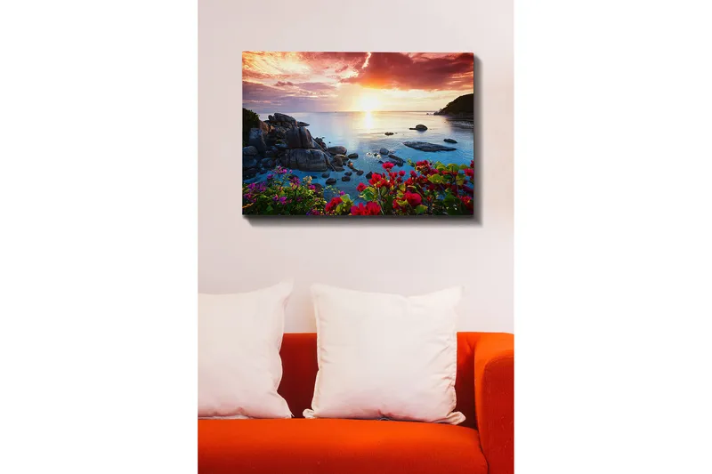 Lerretsbilde 70x100 cm - Vakker solnedgang over havet med steiner og fargerike blomster i forgrunnen - Rosa / Blå / Oransje - Innredning - Bilder & kunst - Lerretsbilder
