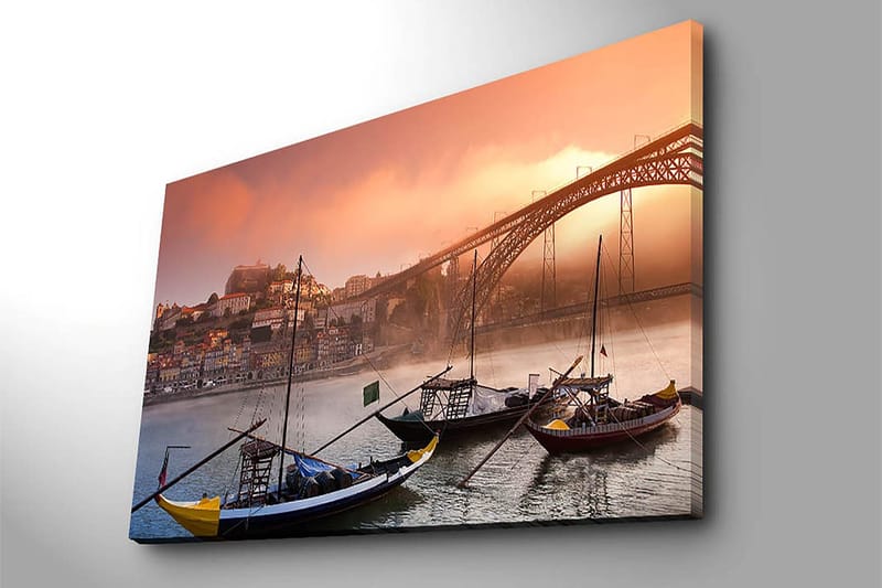 Lerretsbilde 70x100 cm - Vakker utsikt over elven med tradisjonelle båter og en majestetisk bro i bakgrunnen, omgitt av fargerike hus - Oransje / Blå / Gul - Innredning - Bilder & kunst - Lerretsbilder