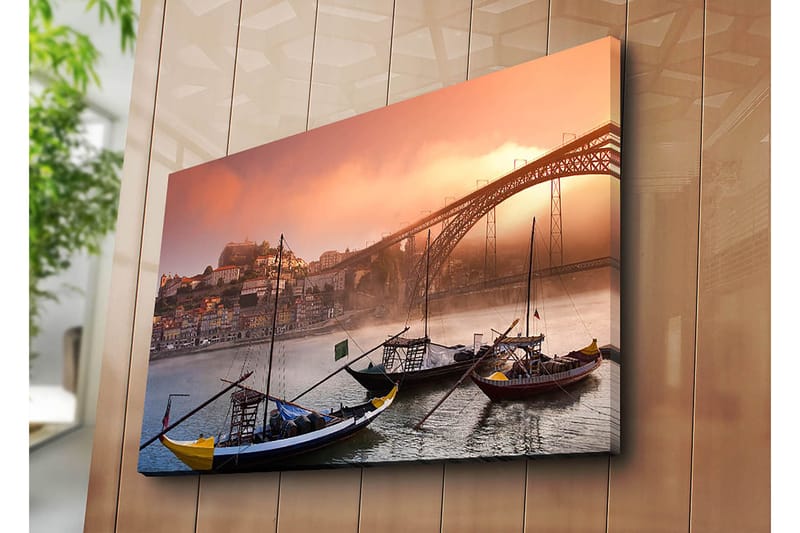 Lerretsbilde 70x100 cm - Vakker utsikt over elven med tradisjonelle båter og en majestetisk bro i bakgrunnen, omgitt av fargerike hus - Oransje / Blå / Gul - Innredning - Bilder & kunst - Lerretsbilder