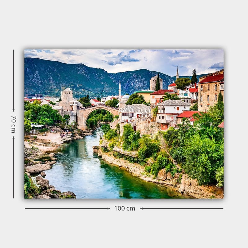 Lerretsbilde 70x100 cm - Vakker utsikt over en historisk bro som krysser en elv, omgitt av pittoreske hus og frodig grøntområde - Grønn / Blå / Rød - Innredning - Bilder & kunst - Lerretsbilder