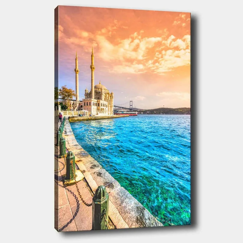 Lerretsbilde 70x100 cm - Vakker utsikt over en moské ved vannet med en bro i bakgrunnen under en fargerik himmel - Blå / Oransje / Beige - Innredning - Bilder & kunst - Lerretsbilder