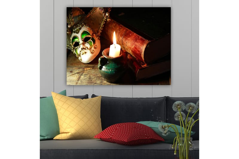 Lerretsbilde 70x100 cm - Venetiansk maske i fokus med et brennende stearinlys og gamle bøker i bakgrunnen - Grønn / Brun / Hvit - Innredning - Bilder & kunst - Lerretsbilder