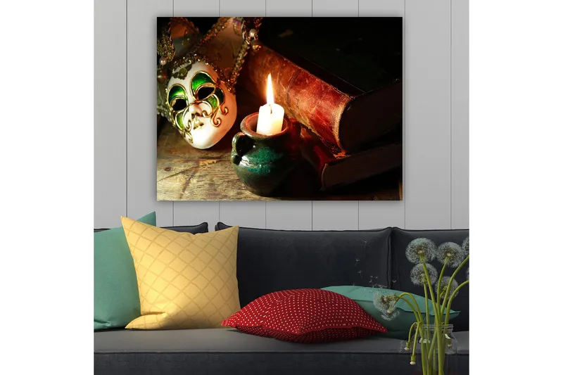 Lerretsbilde 70x100 cm - Venetiansk maske i fokus med et brennende stearinlys og gamle bøker i bakgrunnen - Grønn / Brun / Hvit - Innredning - Bilder & kunst - Lerretsbilder