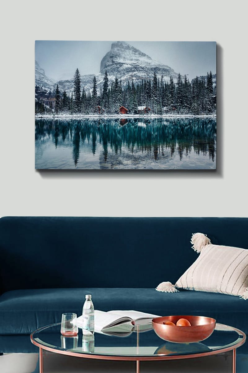 Lerretsbilde 70x100 cm - Vinterlandskap med snødekte fjell og en speilblank innsjø omgitt av grantrær og røde hytter - Mørk grønn / Blå / Hvit - Innredning - Bilder & kunst - Lerretsbilder