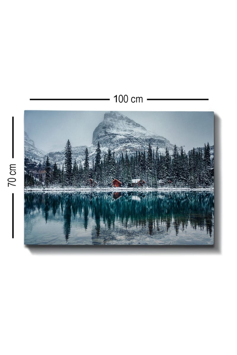 Lerretsbilde 70x100 cm - Vinterlandskap med snødekte fjell og en speilblank innsjø omgitt av grantrær og røde hytter - Mørk grønn / Blå / Hvit - Innredning - Bilder & kunst - Lerretsbilder