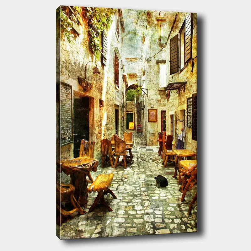 Lerretsbilde 70x100 cm - Pittoresk smug med trebord og stoler, omgitt av gamle steinhus - Brun / Grå / Grønn - Innredning - Bilder & kunst - Lerretsbilder