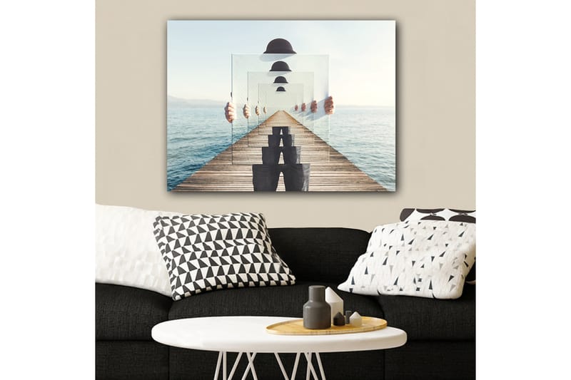 Lerretsbilde 70x100 cm - Person som holder opp flere gjennomsiktige paneler som skaper en illusjon av dybde og perspektiv på en brygge ved vannet - Blå / Svart / Hvit - Innredning - Bilder & kunst - Lerretsbilder
