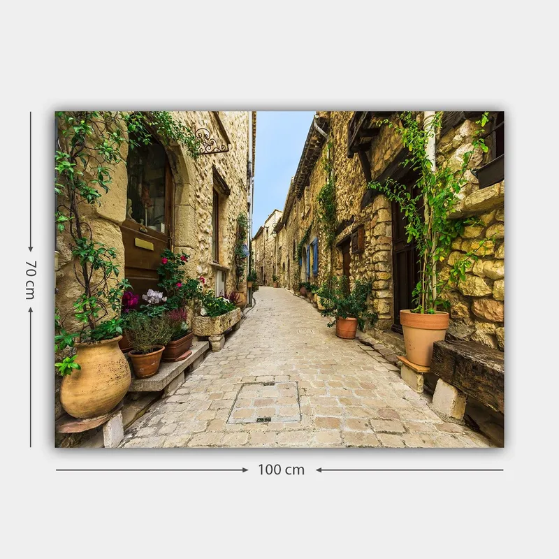 Lerretsbilde 70x100 cm - Pittoresk smug i en gammel landsby med steinhus og blomsterpotter - Beige / Grønn / Terrakotta - Innredning - Bilder & kunst - Lerretsbilder