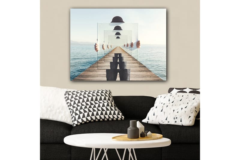 Lerretsbilde 70x100 cm - Person som holder opp flere gjennomsiktige paneler som skaper en illusjon av dybde og perspektiv på en brygge ved vannet - Blå / Svart / Hvit - Innredning - Bilder & kunst - Lerretsbilder