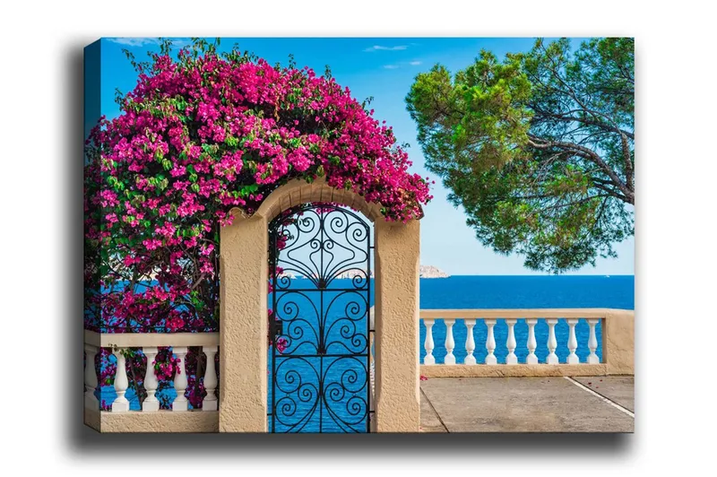 Lerretsbilde - Blomstrende bougainvillea ved en smijernsport med havutsikt, Rosa / Blå / Grønn