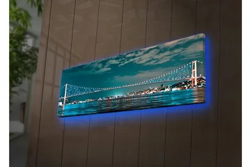Lerretsbilde med LED-belysning 30x90 cm - Bro over et rolig vann med bylys i bakgrunnen - Mørk blå / Turkis / Lys grønn - Innredning - Bilder & kunst - Lerretsbilder